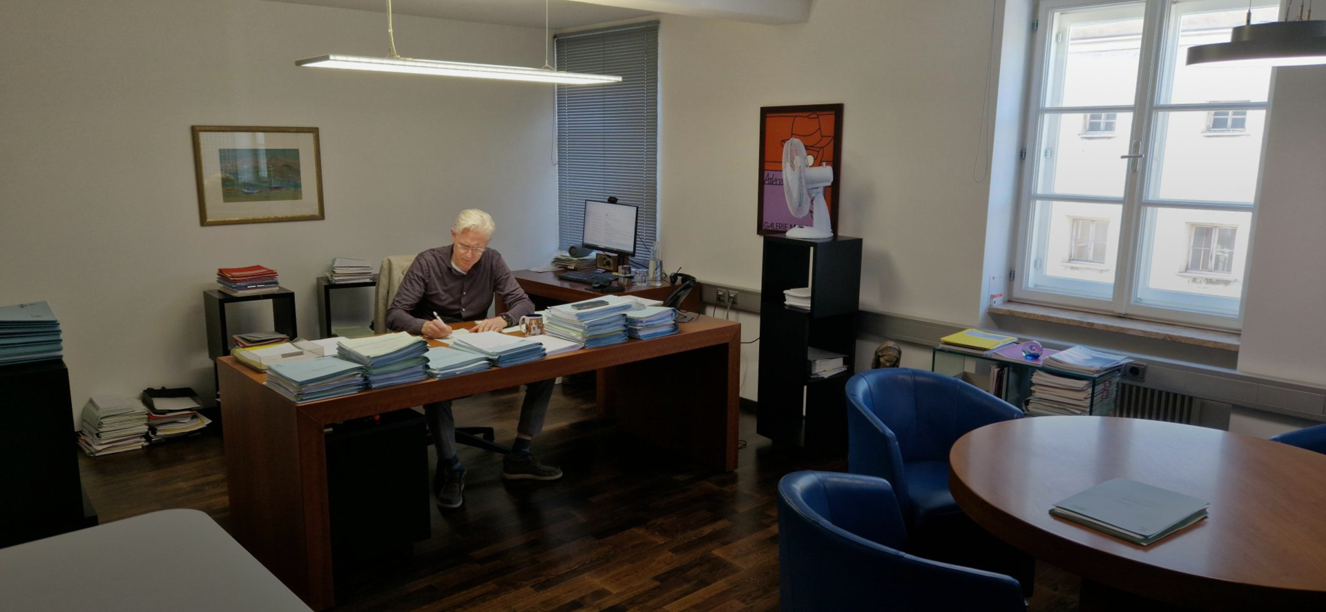 Ein Mann sitzt an einem Schreibtisch in einem Büro und arbeitet konzentriert an seinem Computer.